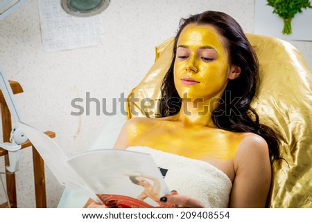 Beautiful brunette in a spa salon. Girl taking facial treatment at the salon. Facial treatment, gold mask, beauty, spa, mask - Concept of facial skin care. Article about koosmetologiyu.