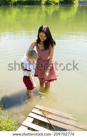 Mother and son on the lake. Standing knee-deep in water, cool in hot weather and communicate with each other.Nature, lake, swimming, baby - The concept of country vacation. article about the rest.