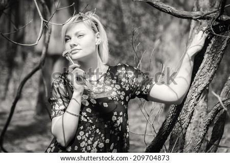 Black and white. Beautiful blonde in a garden. Girl enjoying nature. Garden, beauty, trees, - concept of enjoying nature. Idea of  the article about the garden and nature.