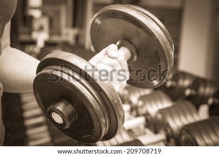Girl at the gym. Hand holding a dumbbell. Girl doing exercises with dumbbell. Sports, fitness, dumbbell, gym - Concept of force, sport, health. Article about bodybuilding.