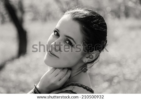 Black and white. Beautiful brunette in a lush spring garden. Girl enjoying flowering trees. Garden, beauty, flowers, - concept of enjoying nature. Idea of the article about the garden and nature.