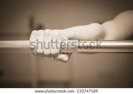 The beautiful blonde in the gym. The girl is engaged in strength training. Holding hand on barbell. Exercise, fitness, sports, health. Healthy lifestyle concept. Article about the sport
