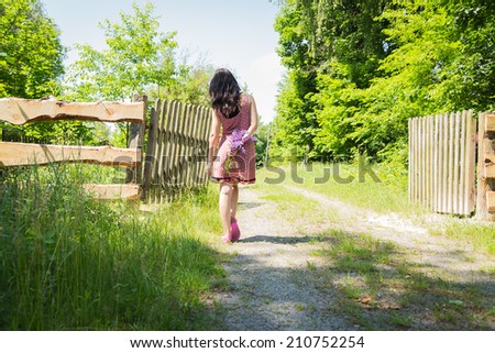 Girl with blue flowers. The girl stands near a wooden fence and smelling flowers. Flowers, girl, holiday, vacation holiday. The concept of happiness and carefree.