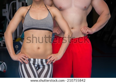 Man and woman in the gym. Fitness, sport, training, gym and lifestyle concept - two smiling people standing in the gym. The idea of article about sport and fitness.