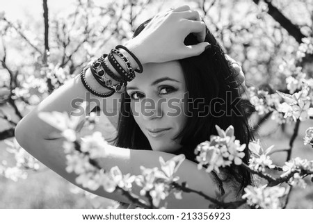 Black and white. Beautiful brunette in a lush spring garden. Girl enjoying flowering trees. Garden, beauty, flowers, - concept of enjoying nature. Idea of ??the article about the garden and nature.