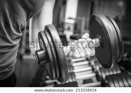 Muscular arm in the gym. in suspense. Training, sports, hand, dumbbell, trainnings. - The concept of a healthy lifestyle and fitness. article about fitness and sports.
