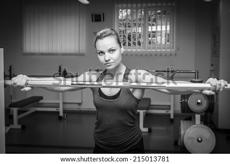 The beautiful blonde in the gym. The girl is engaged in strength training. Holding hand on barbell. Exercise, fitness, sports, health. Healthy lifestyle concept. Article about the sport