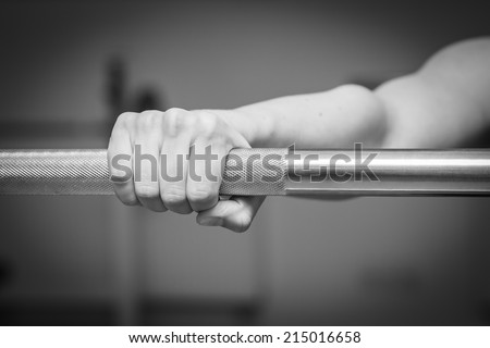 Girl\'s hand on the barbell. Beautiful girl goes in for sports in the gym. Girl holding a barbell. Gym, strength, fitness - Healthy lifestyle concept. Article about women\'s fitness.