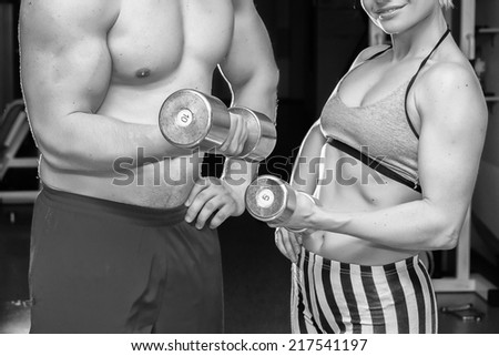 Athletic man and woman with a dumbells.Fitness, sport, training, gym and lifestyle concept - two smiling people working out with dumbbells in the gym.couple in the gym, exercising with dumbbells