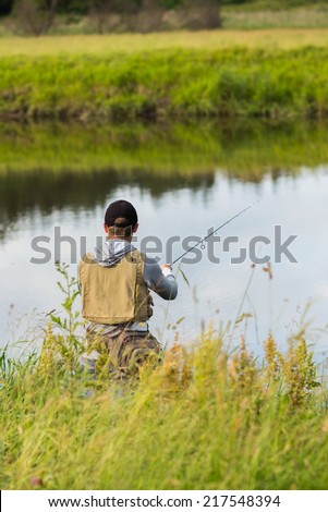 Fishing in river.A fisherman with a fishing rod on the river bank. Man fisherman catches a fish.Fishing, spinning reel, fish, Breg rivers. - The concept of a rural getaway. Article about fishing.