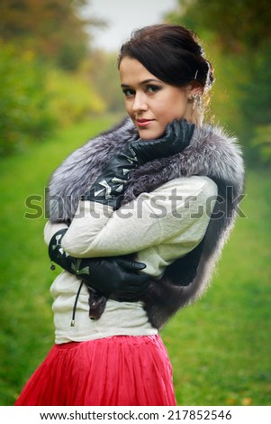 stylish beautiful girl posing outdoors in fur scharf,  and leather gloves
