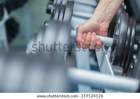 Hand holding dumbbell.Close up.Muscular arm in the gym. Training, sports, hand, dumbbell, trainnings. - The concept of a healthy lifestyle and fitness. article about fitness and sports.