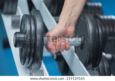 Hand holding dumbbell.Close up.Muscular arm in the gym. Training, sports, hand, dumbbell, trainnings. - The concept of a healthy lifestyle and fitness. article about fitness and sports.