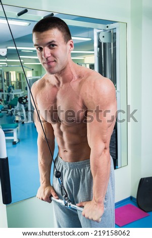 Man with weight training equipment on sport gym club.Man makes exercises. Sport, power, dumbbells, tension, exercise - the concept of a healthy lifestyle. Article about fitness and sports.