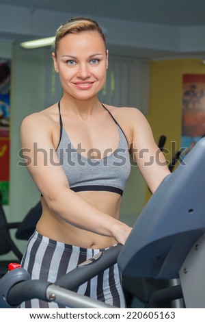 Cute young woman exercising on a treadmill at a gym.Attractive young fitness model runs on a treadmill, is engaged in fitness sport club