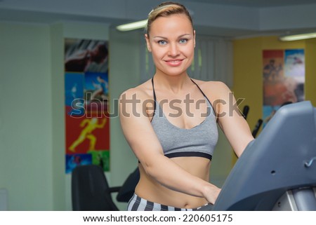 Cute young woman exercising on a treadmill at a gym.Attractive young fitness model runs on a treadmill, is engaged in fitness sport club