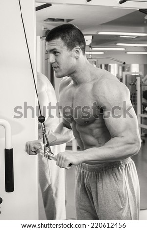 athlete doing fitness training on machine with weights in a gym.Sport, power, dumbbells, tension, exercise - the concept of a healthy lifestyle. Article about fitness and sports.