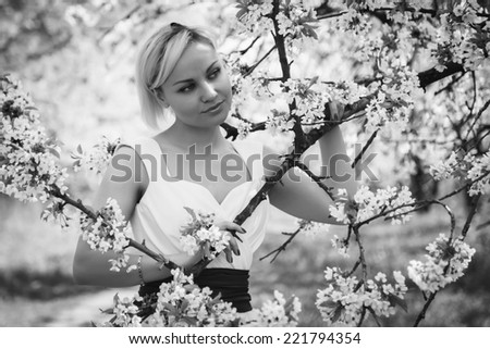 Beautiful happy blonde woman in the park on a warm summer day.Portrait of young lovely woman in spring flowers.Beautiful spring girl in blooming tree.Beautiful woman with white flowering tree