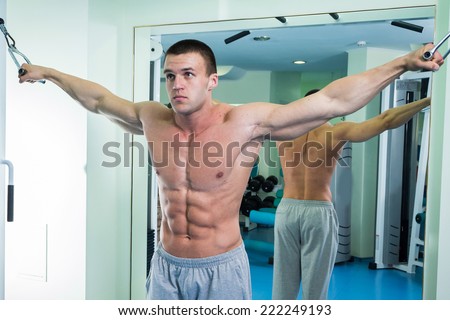 Fit man exercising at the gym on a machine.Man at the gym. Man makes exercises. Sport, power, dumbbells, tension, exercise - the concept of a healthy lifestyle. Article about fitness and sports.