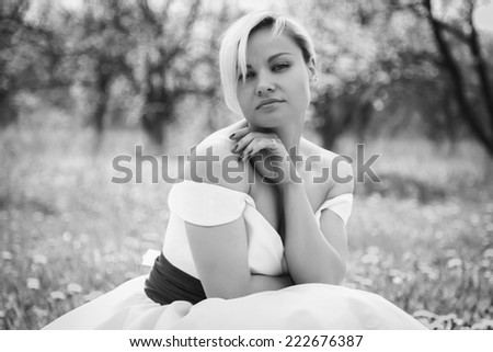 Beautiful happy blonde woman in the park on a warm summer day.Portrait of young lovely woman in spring flowers.Beautiful spring girl in blooming tree.Beautiful woman with white flowering tree