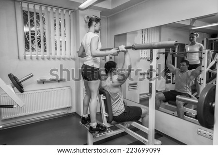 Gym man exercising with his personal trainer.Man with his personal fitness trainer in the gym exercising with athletic Rod.Sport, power,dumbbells tension,exercise - the concept of a healthy lifestyle.