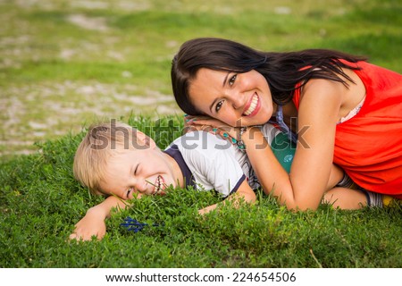 Mom and son outdoors. Mom and son lying on the grass. Mom hugging her son. Holidays, family, nature, children - the concept of a family holiday in the countryside.