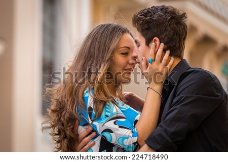 Young affectionate couple kissing tenderly.Young couple in love traveling around the beautiful city. Young people hugging and kissing on the streets.Young couple in love, hugging on the street.