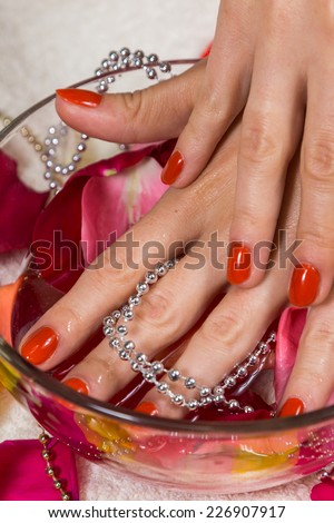 Manicure - Beautiful manicured woman's hands with red nail polish on rose petals.Beautiful hands with a nice manicure. Gel nails are covered with red polish. Spa treatment for hands.