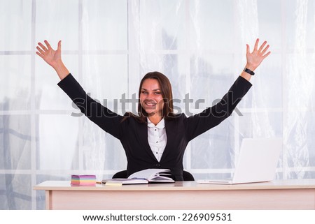 Young pretty business woman with notebook in the office.Successful business woman with arms up - isolated over a white background