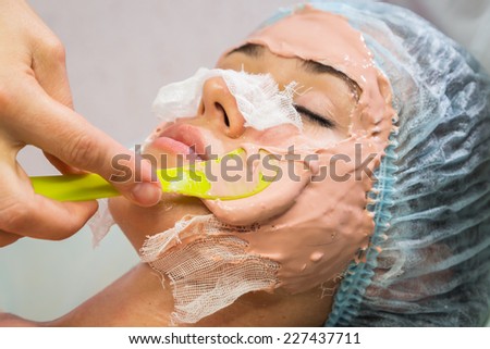 Beautiful woman with facial mask at beauty salon.Pretty woman receiving facial massage.Spa therapy for young woman receiving facial mask at beauty salon - indoors