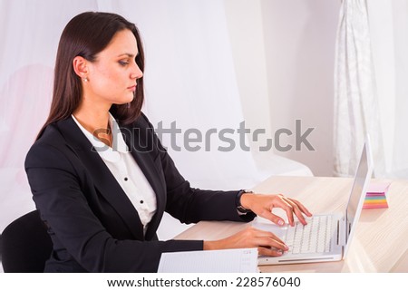 Business woman working in the office at the table.young business woman reading sitting at the desk on office background.Portrait of businesswoman with laptop writes on a document at her office