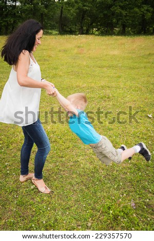 Mom and son in the summer field. Mother playing with her son. Mother and son having a great weekend. Games, field, family weekend - family-friendly concept. Article about the family.