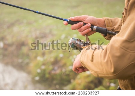 Fisherman on the river bank. Autumn fishing. Fisherman in his hand holding spinning. Fishing, spinning reel, fish, Breg rivers. - The concept of a rural getaway. Article about fishing.
