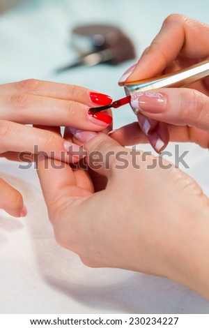 Manicure in the spa salon. Drawing of red nail polish. Spa manicure, nail care. Girl does a manicure. The concept of hand care.