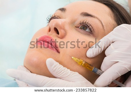 Beauty, health and people concept - hands in medical glove with syringe making injection to beautiful woman in spa clinic.osmetic injection in the spa salon.