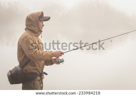 Fisherman on the autumn background. Fisherman in his hand holding spinning. Fishing, spinning reel, fish, Breg rivers. - The concept of a rural getaway. Article about fishing.