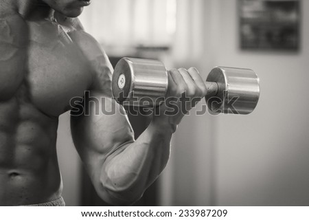 Strong and muscular guy with dumbbell. Handsome muscular man working out with dumbbells in gym.Sport, power, dumbbells, tension, exercise - the concept of a healthy lifestyle.