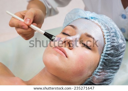 Girl with a beautician at spa salon. Beautician performs cosmetic procedures.applying cosmetic cream. Cosmetology, facial, beauty - The concept of facial skin care. Article about cosmetology.