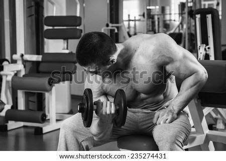 Fit man exercising at the gym on a machine.Man at the gym. Man makes exercises. Sport, power, dumbbells, tension, exercise - the concept of a healthy lifestyle. Article about fitness and sports.