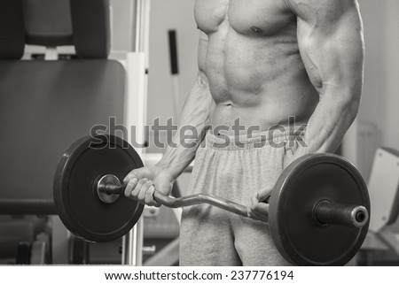 Man at the gym. Man makes exercises with barbell. Sport, power, dumbbells, tension, exercise - the concept of a healthy lifestyle. Article about fitness and sports.