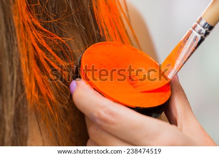 Hair coloring brush, painting hair orange. Makeup artist in the salon hair color model. Creativity, makeup, make-up, hair coloring.
