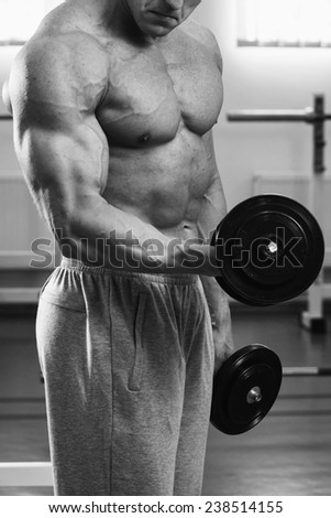 Muscular arm in the gym. Hand holding a dumbbell in suspense. Training, sports, hand, dumbbell, trainnings. - The concept of a healthy lifestyle and fitness. article about fitness and sports.