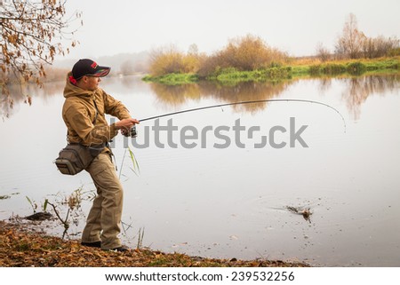 Fisherman on the autumn background. Fisherman in his hand holding spinning. Fishing, spinning reel, fish, Breg rivers. - The concept of a rural getaway. Article about fishing.