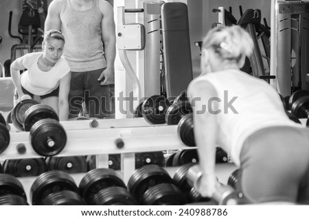 Man and woman trained in the gym. Trainer demonstrates exercises, girl. Loving couple in the gym. Family fitness, exercise, coaching - team work in the gym.