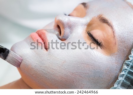 Application of the silver mask on the face of the girl. Cosmetic procedures for the face. Beautician facial treatment at a spa salon. The procedure to rejuvenate and nourish the skin of the face.