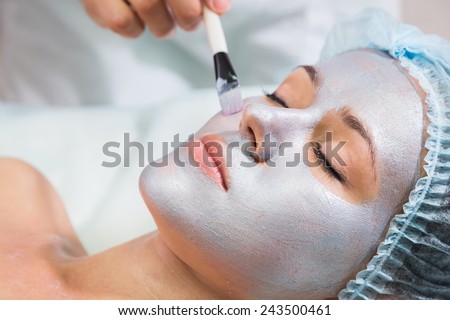 The cosmetic procedures for the face. Makeup artist applies invigorating mask on the face of the model. Beauty treatments in the spa salon. Facial Skin Care.