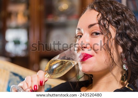 Beautiful young brunette woman drinking champagne. Gorgeous girl holding a glass of champagne.