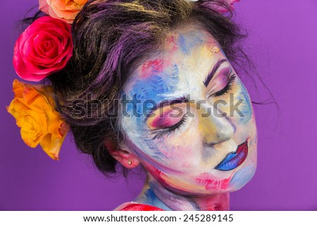 Artistic work of make-up artist. Flower girl. Roses woven into the hair model. Art, fashion, make-up. Girl on a purple background. Multicolored make-up. Roses in the hair.
