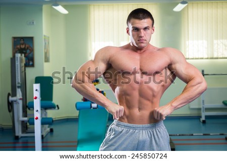 Bodybuilder man posing in GYM. The very power athletic guy standing in the gym, workout at the gym