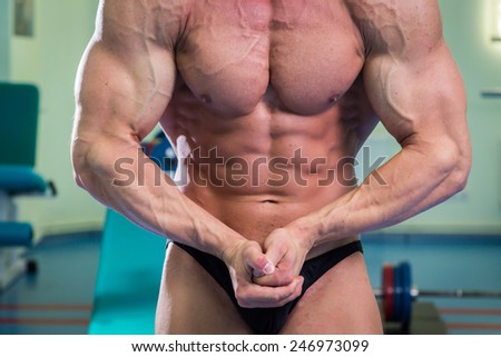 Handsome muscular male body. Male bodybuilder. Muscles of the arms, torso, abdominal muscles. Bodybuilding pose. Concept Proffesional bodybuilding.